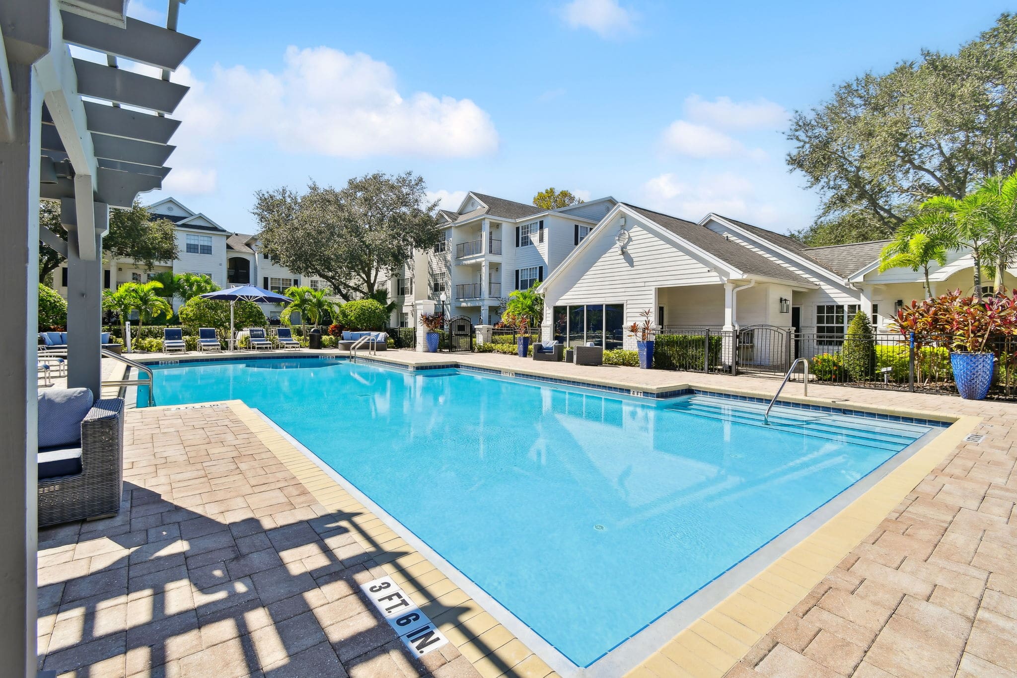 Downtown Orlando, FL, Luxury Apartments For Rent - Infinity Off Baldwin Park - Resort-Style Pool And Sundeck, Lounge, Tanning Chairs, And Blue Umbrellas.